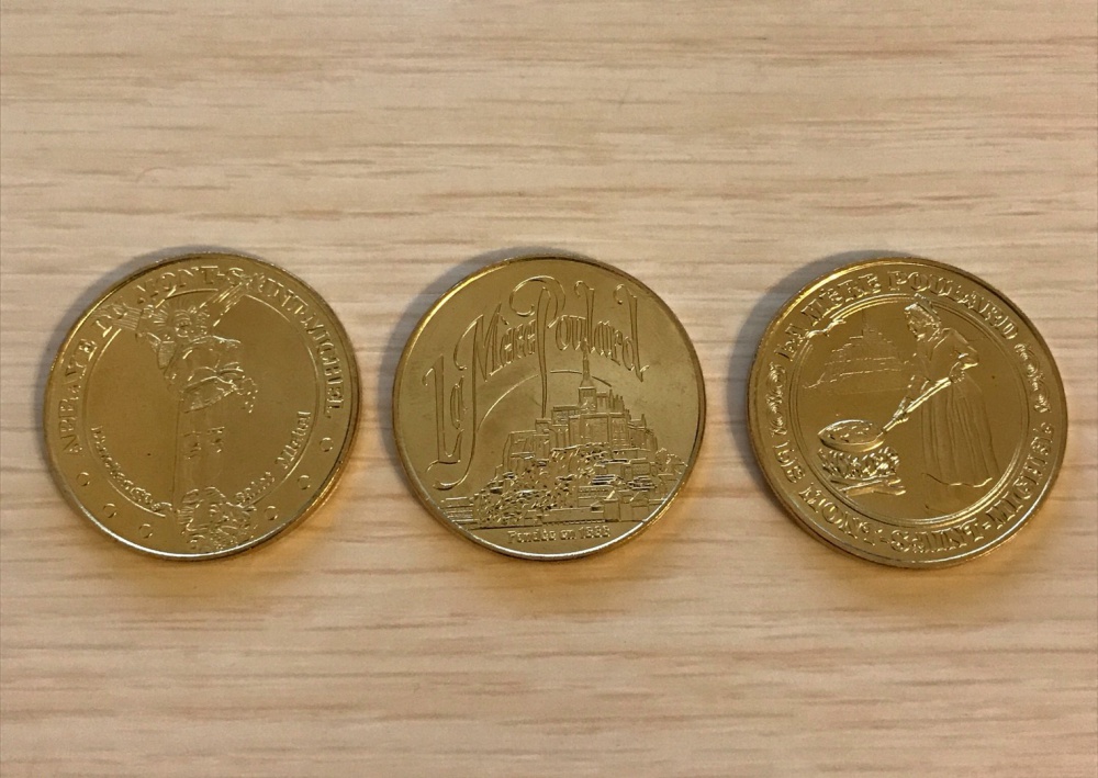 右からミカエル様、モン・サン＝ミシェル、卵料理の絵柄をした記念コイン。特に真ん中のコインが人気で売り切れでした。